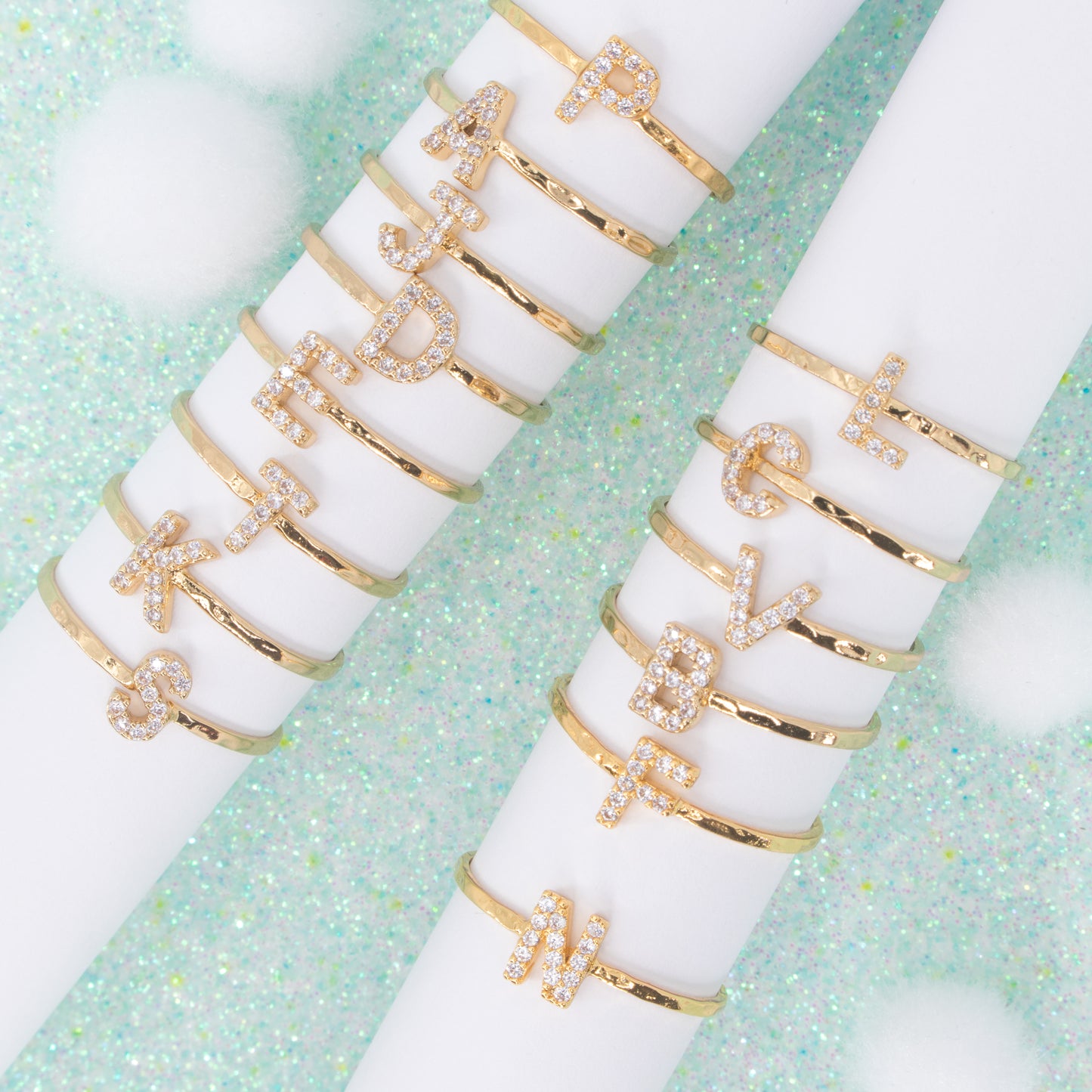 gold sparkling monogram rings on white ring holders