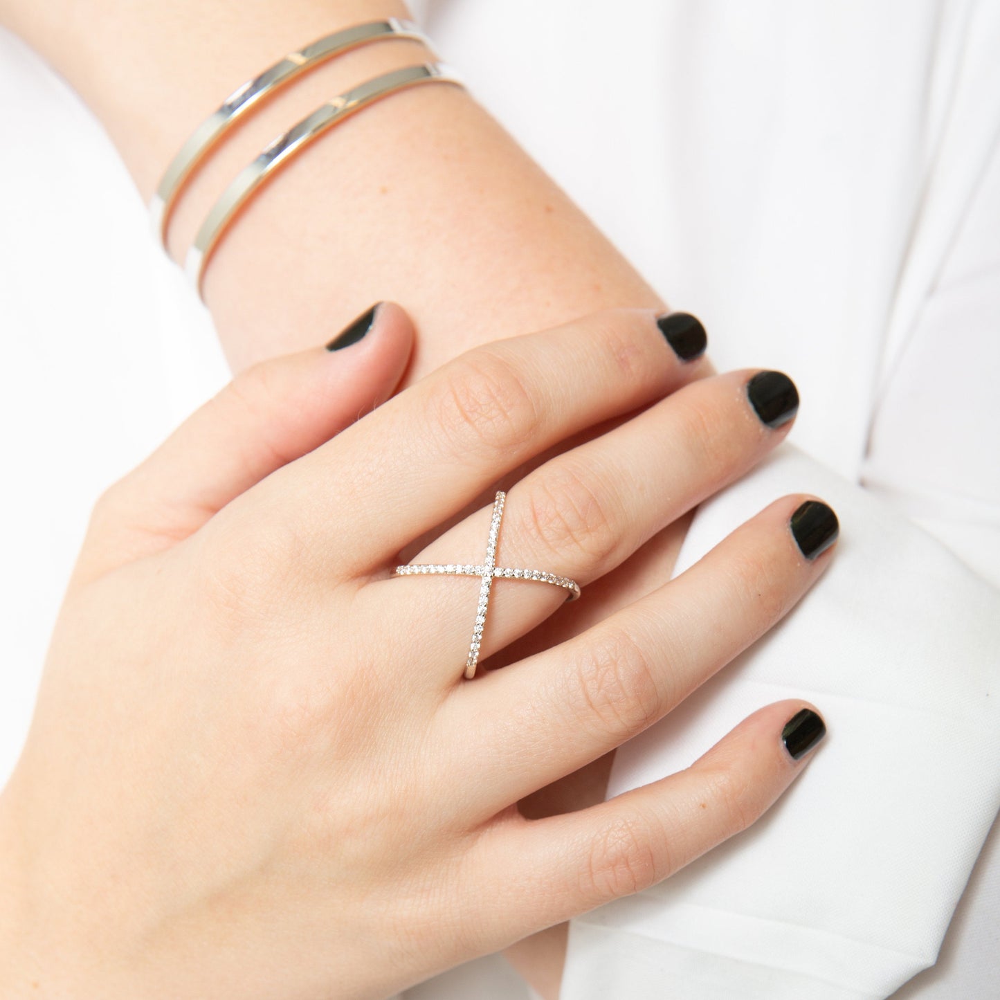 silver pavé cross ring on middle finger